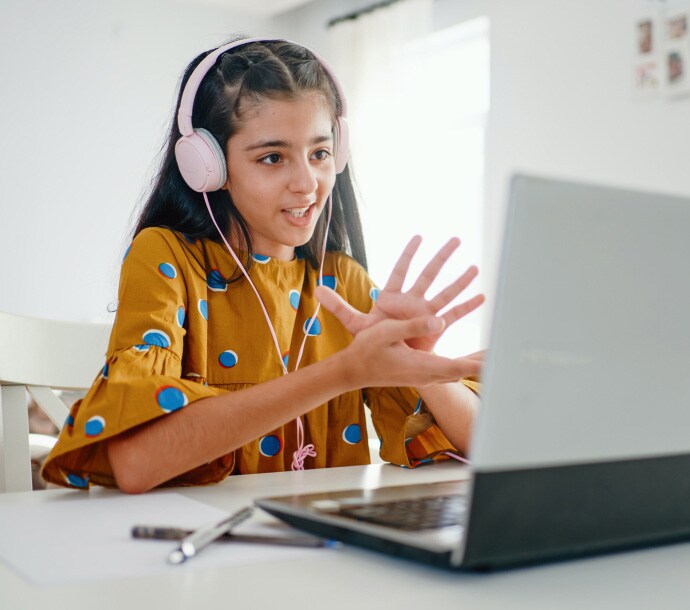 机に向かい、ノートパソコンでノートン ファミリーを起動している女の子。