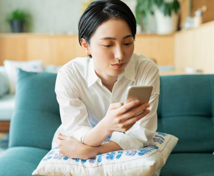 バルコニーで携帯電話を持つ若い女性。
