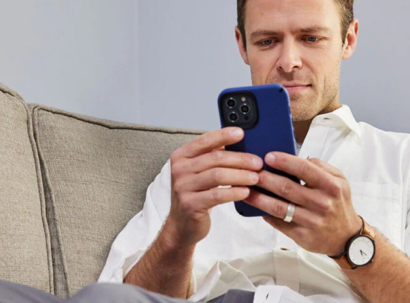 ソファで携帯電話を見ている男性