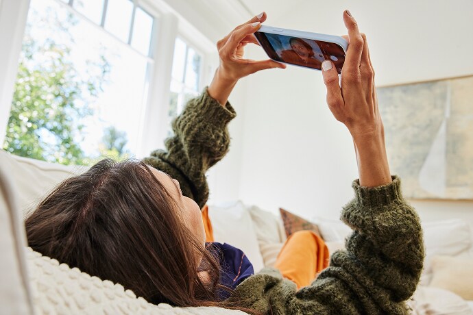 寝そべって携帯電話を見ている女性